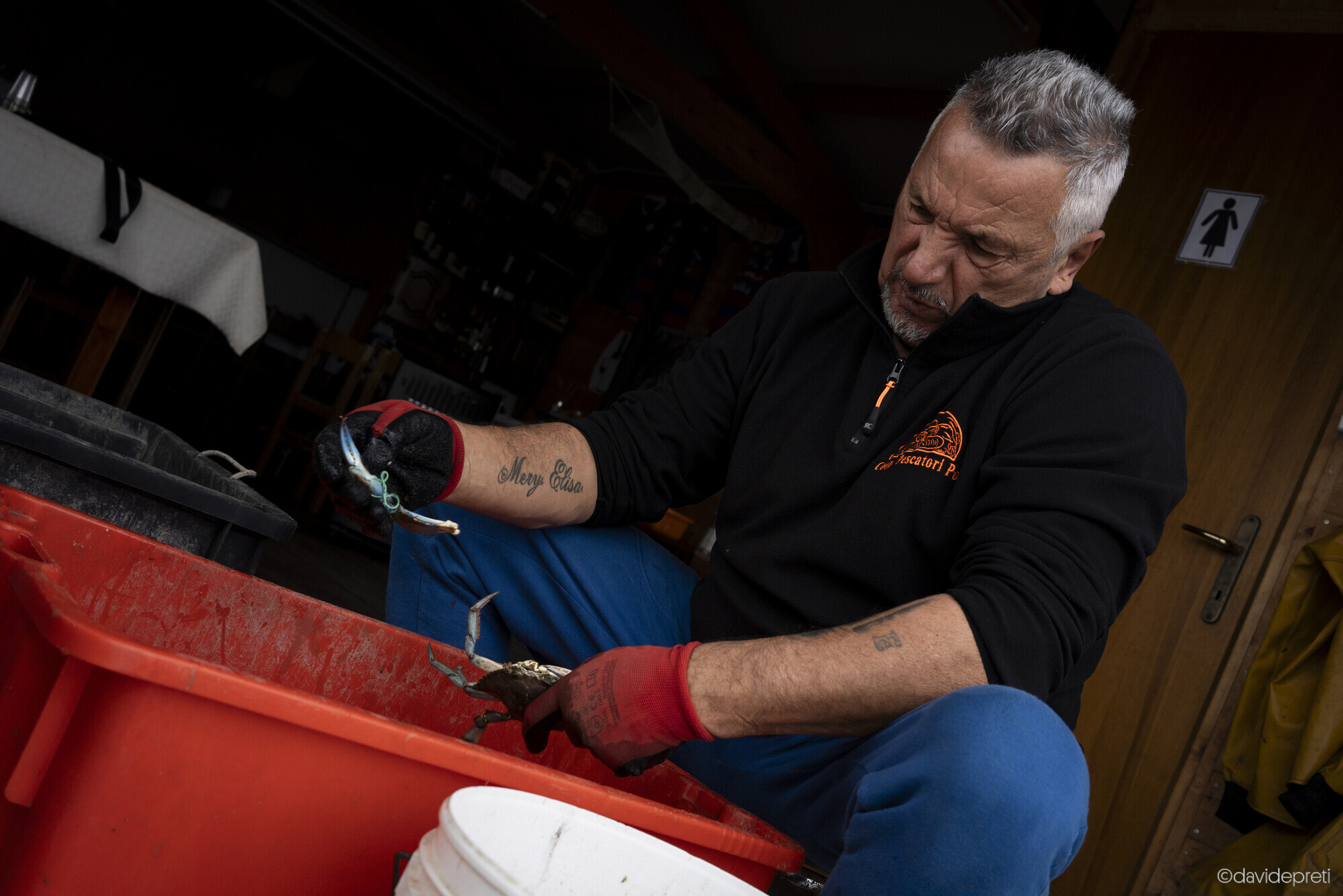 Scardovari Lagoon, Italy — November 8, 2024.

Massimo cleaning a blue crab at the edge of his cavana, ahead of a family lunch.
