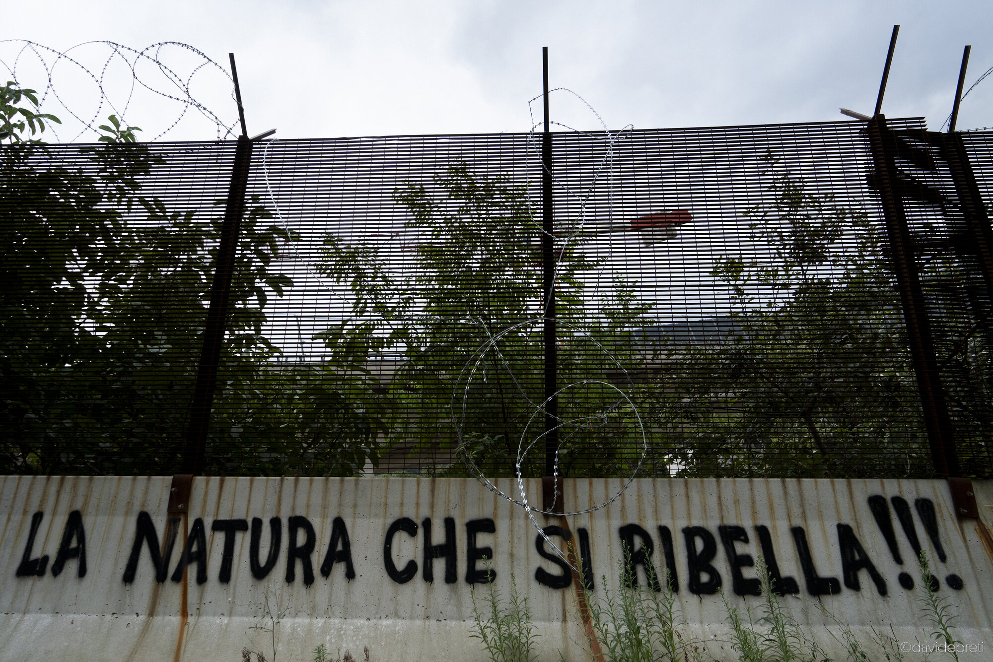 Val di Susa, Italy — September 17, 2024.

Anti-high-speed rail graffiti visible on concrete Jersey barriers surrounding the Lyon-Turin high-speed rail line (TAV) construction site in the Susa Valley.
